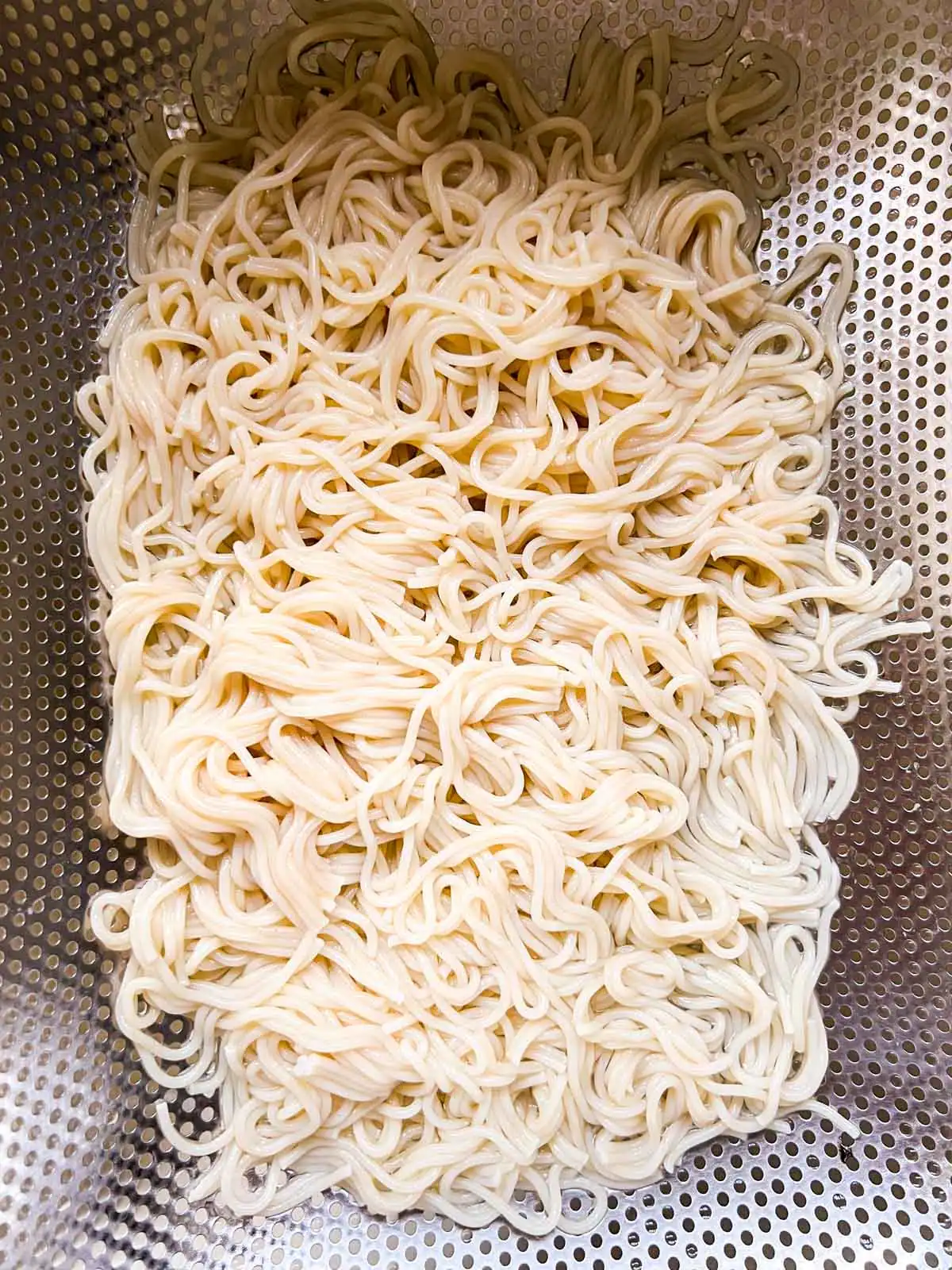 Ramen noodles draining in a colander.