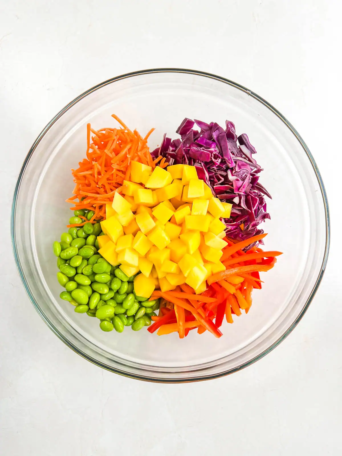 Ingredients for mango peanut noodle salad in a glass bowl.