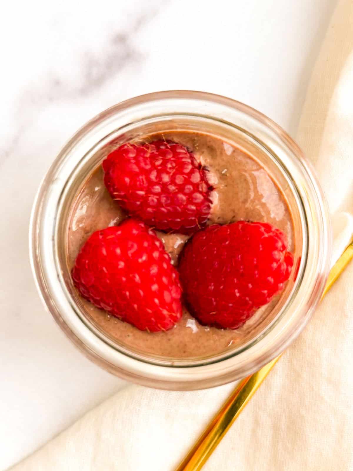 Vegan chocolate mousse topped with raspberries.