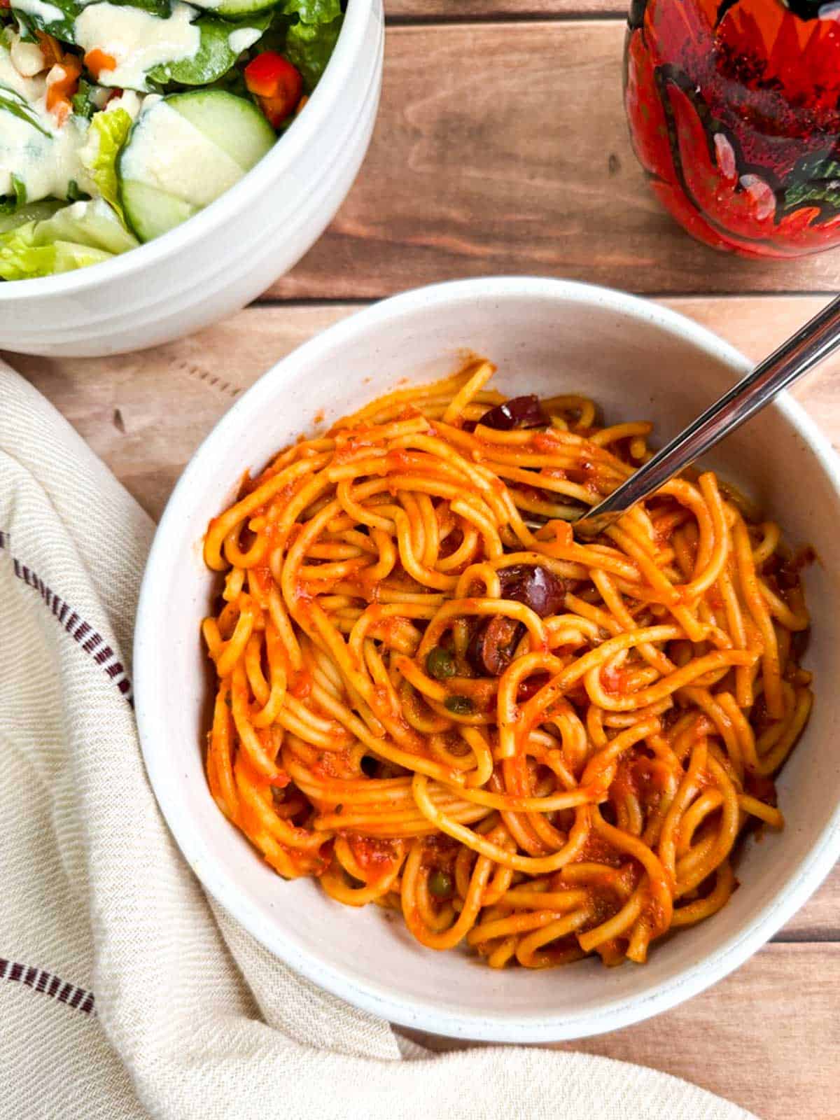 A bowl of Instant Pot spaghetti next to a salad.