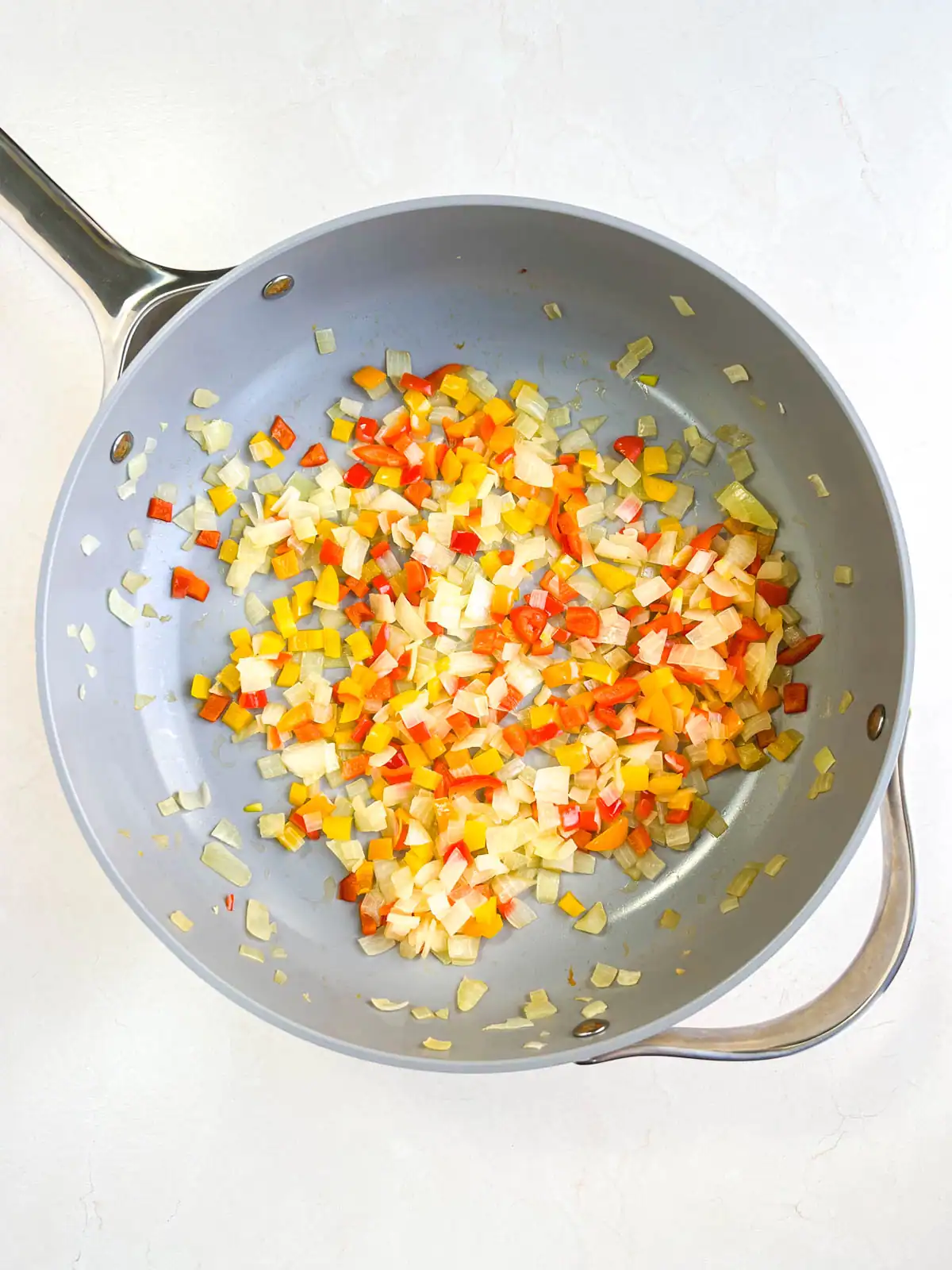Diced onions and peppers in a skillet.