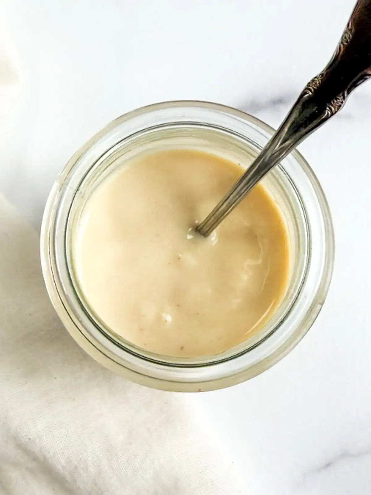 Overhead view of vegan Caesar dressing in a glass jar.